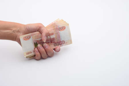 Hand holds a stack of five thousandth bills in a fist