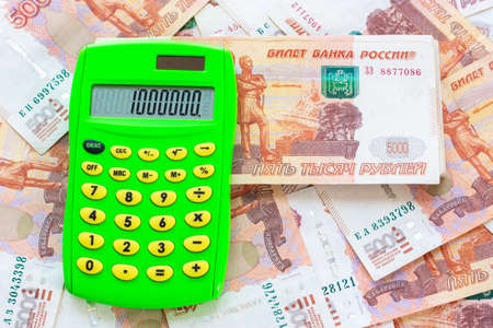 The number 1,000,000 is written on the calculator, the calculator lies on a pile of moneyの写真素材