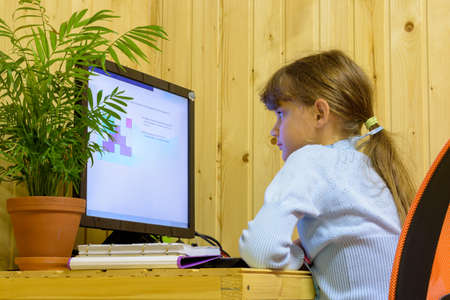 A girl solves a problem on a computer during distance learning