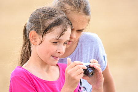 Two girls watching photos on the screen of a digital cameraの写真素材