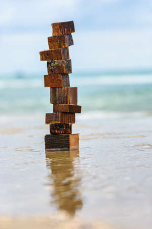 A tower made of wet pieces of wood stands on the wave-laden seashore