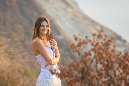Beautiful girl in a white dress on a background of mountainsの写真素材