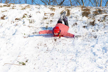 A girl is rolling down a snow-covered slide upside down