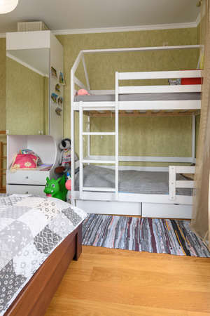 Fragment of the interior of a bedroom with a large double bed and a children's bunk bed