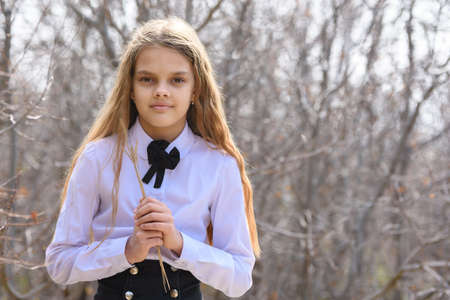 Portrait of a beautiful twelve-year-old girl with dried wildflowers in her hands on a forest backgroundの写真素材