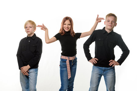 Happy children on a white background, a girl put impromptu pistols to the heads of brothersの写真素材