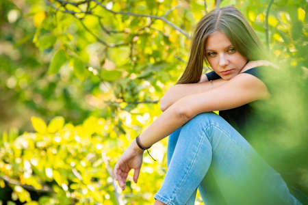 Sad girl ponders the situation while in a green parkの写真素材
