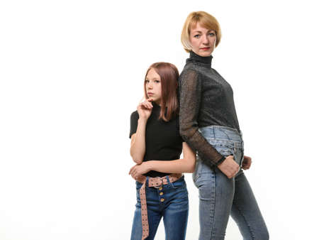 Portrait of a teenager girl and a woman, the girl looks thoughtfully to the left, the woman looks into the frameの写真素材