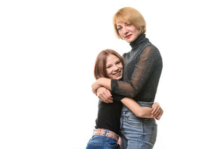 Happy daughter hugs her mother, both look joyfully into the frame, close-up portraitの写真素材