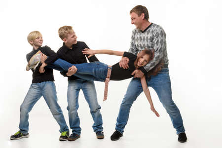 Dad and sons stretch sister by the arms and legs, white backgroundの写真素材