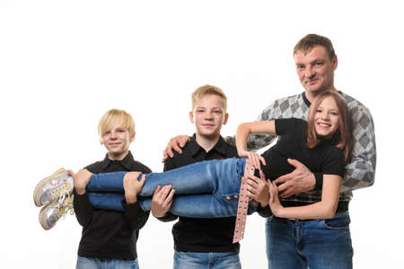 Dad and two sons holding a teenage girl in their arms, casual wear in dark colors, white backgroundの写真素材