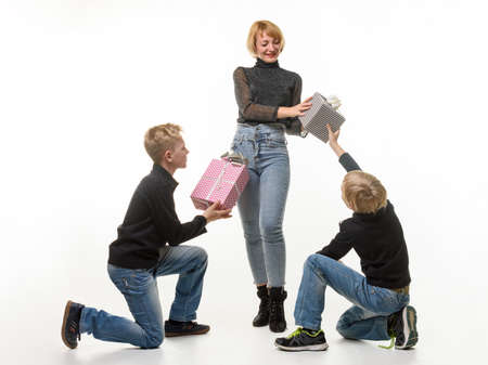 Children give a gift to mom, kneeling, mom picks up one of the gifts, white backgroundの写真素材