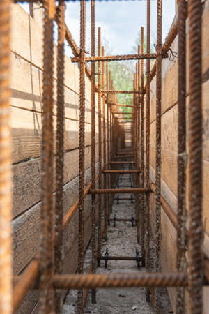 Close-up of tied reinforcement and mounted strip foundation formwork, view inside the trench