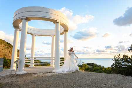 Portrait of a bride in a wedding dress in a beautiful gazebo with columns on the seashoreの写真素材
