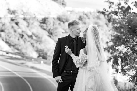 Happy newlyweds kiss against the backdrop of a beautiful mountain landscape, the girl and the guy look at each other passionatelyの写真素材