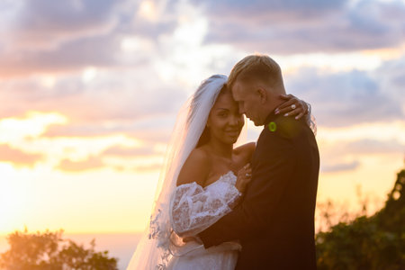Happy newlyweds hugging against the background of a backlit sunsetの写真素材