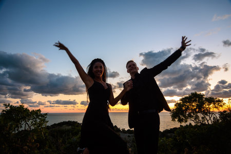 Happy young couple backlit against sunset backgroundの写真素材