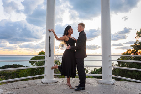 A young couple in a gazebo against the backdrop of a beautiful landscape, the girl holds the guy's tieの写真素材