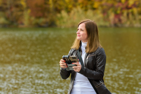 A young beautiful girl launches a radio-controlled quadcopter on the shore of an autumn lake, the...