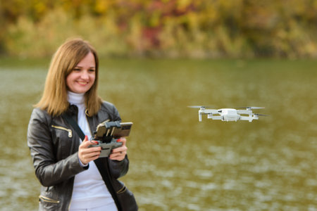 A young beautiful girl launches a radio-controlled quadcopter on the shore of an autumn lake, the...