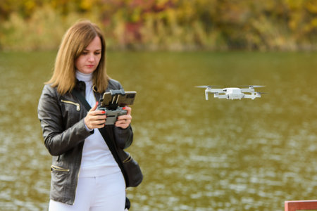 A young girl launches a radio-controlled quadcopter on the shore of an autumn lake