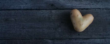 Heart shaped potato on a wooden tableの写真素材