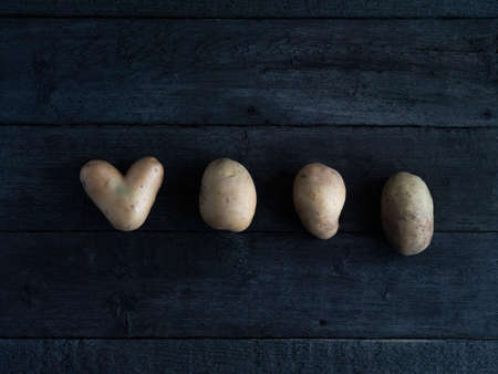 heart-shaped potatoes. wood texture. background old panelsの写真素材