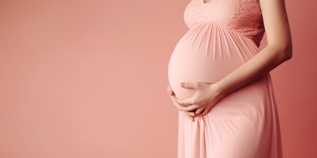 Young, pregnant woman on pink background.の素材
