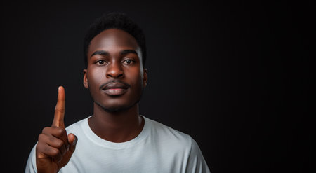 Young african american man pointing up with finger on black backgroundの素材