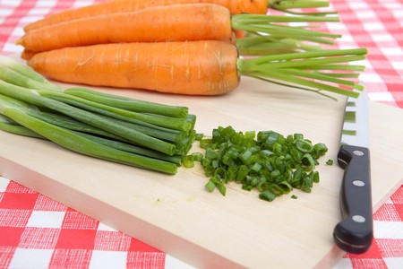 Chopped Spring Onion and Carrots on a Chopping Boardの写真素材