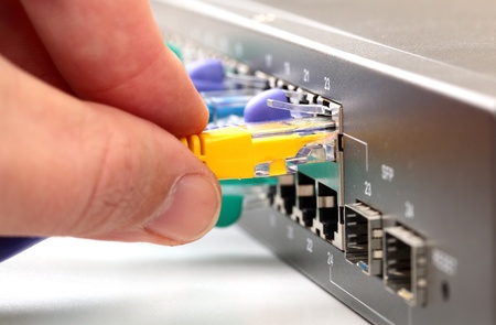 Hand connecting yellow internet cable to hubの写真素材