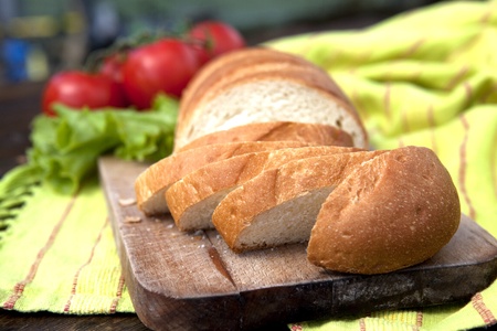 Fresh Bread On Chopping Board With Tomatoes And Salad In The Backgroundの写真素材