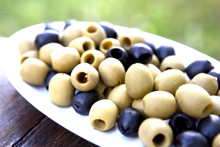 Olives On A Plate On A Old Wooden Table With Green Grass In The Backgroundの写真素材