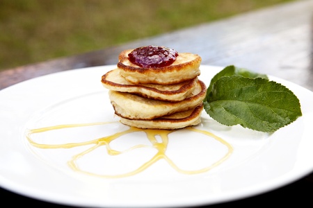 Pancakes On A Plate Covered With Jam And Maple Syrup With Mint On The Sideの写真素材