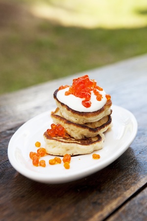 Pancakes On A Plate Covered With Sour Cream And Caviar On An Old Wooden Tableの写真素材