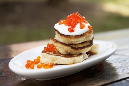 Pancakes On A Plate Covered With Sour Cream And Caviar On An Old Wooden Tableの写真素材