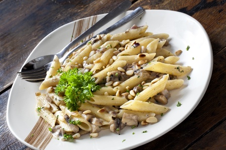 Pasta with Mushrooms and Pine Nuts on a Wooden Tableの写真素材