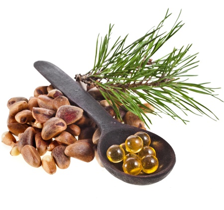 cedar pine nuts and essential oil ball in spoon isolated on white background close upの写真素材