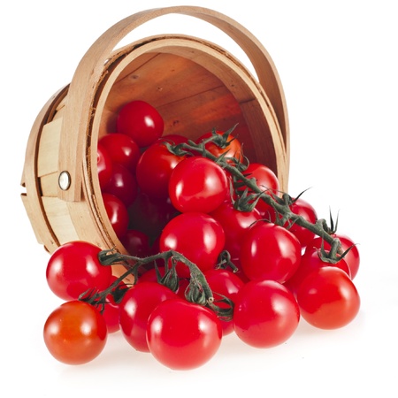 cherry tomatoes in wooden basket isolated on white backgroundの写真素材