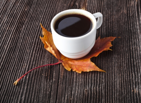 coffee cup on the autumn fall leaves and wooden vintage surface backgroundの写真素材