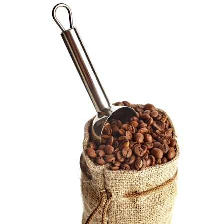 Burlap sack of coffee beans with metallic scoop on white backgroundの写真素材