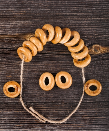 Fun face with curly hair made of sheaf on bagels old ancient wood textureの写真素材