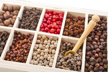 Assortment of different peppercorns in wooden box isolated on whiteの写真素材