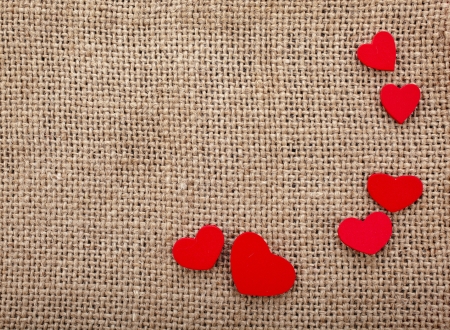 Valentine s day card with wooden red hearts symbol on fabric sack texture backgroundの写真素材