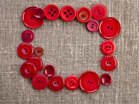 frame of red buttons on canvas burlap background textureの写真素材