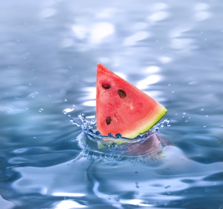 slice watermelon falling in a refreshing drinkの写真素材