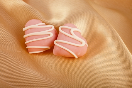 Sweet Pink Marzipan heart candy on golden silk textured cloth card backgroundの写真素材