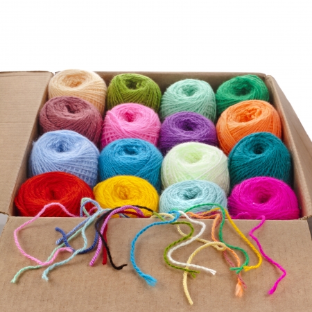 colorful different thread balls of knitting yarn in a cardboard box isolated on white backgroundの写真素材