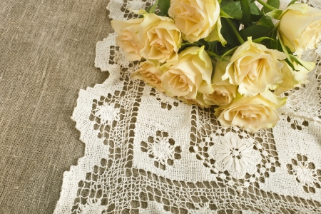 Wedding card with bunch of fresh cream roses on canvas texture with retro crochet doilyの写真素材