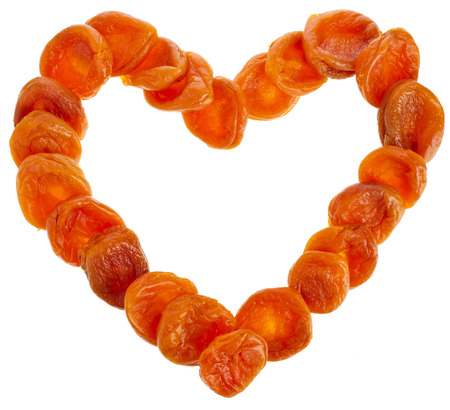 Dried Apricots in shape heart frame card isolated on white backgroundの写真素材